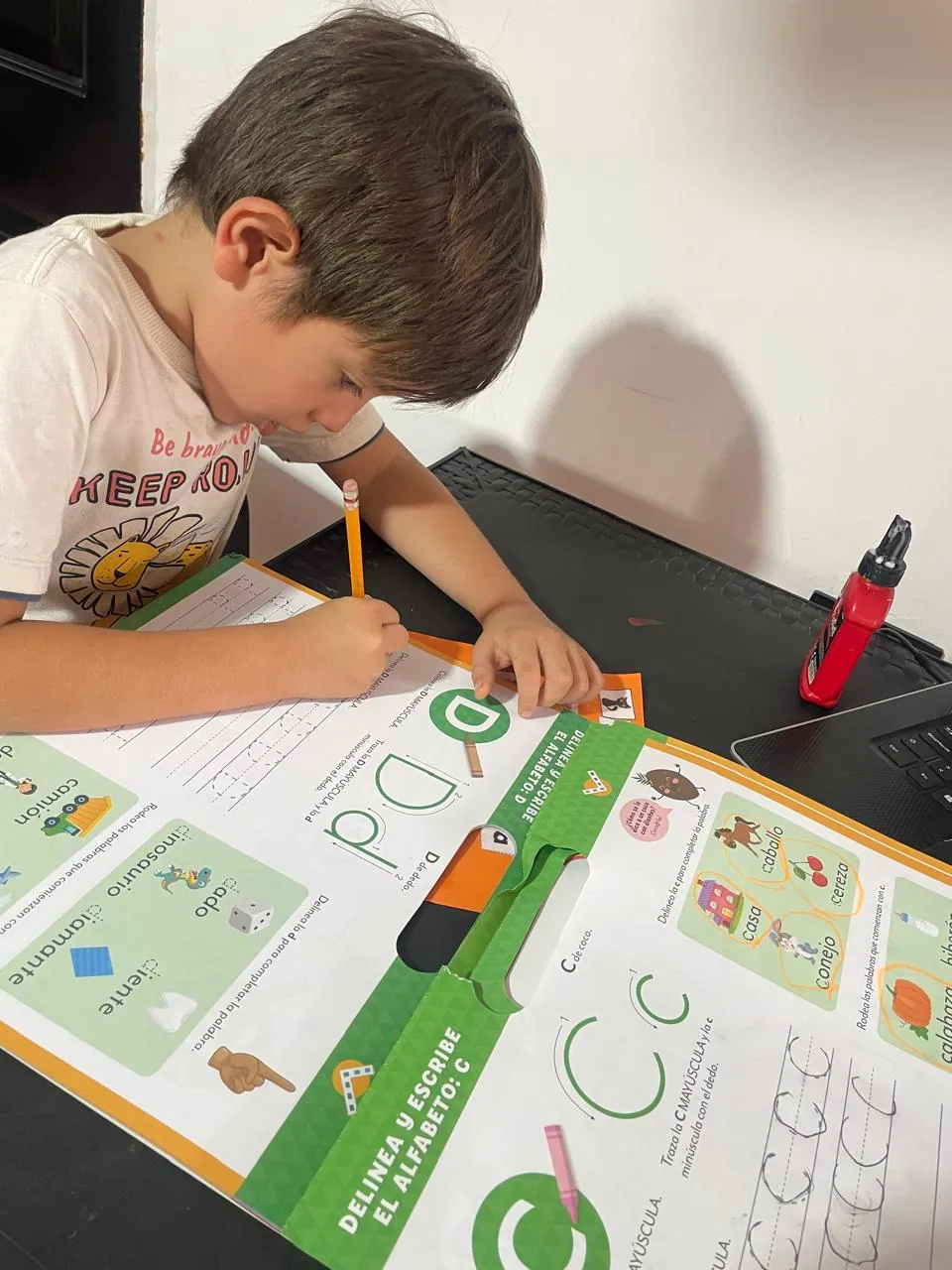 Niño escribiendo letras en una guía de trabajo durante una tutoría de Ritmo Propio
